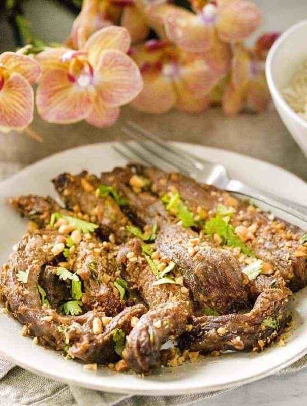 White plate containing Air Fried Beef Satay topped with fresh cilantro.