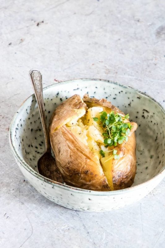 Baked Potato cooked in an Instant Pot sitting in a bowl on a white counter.