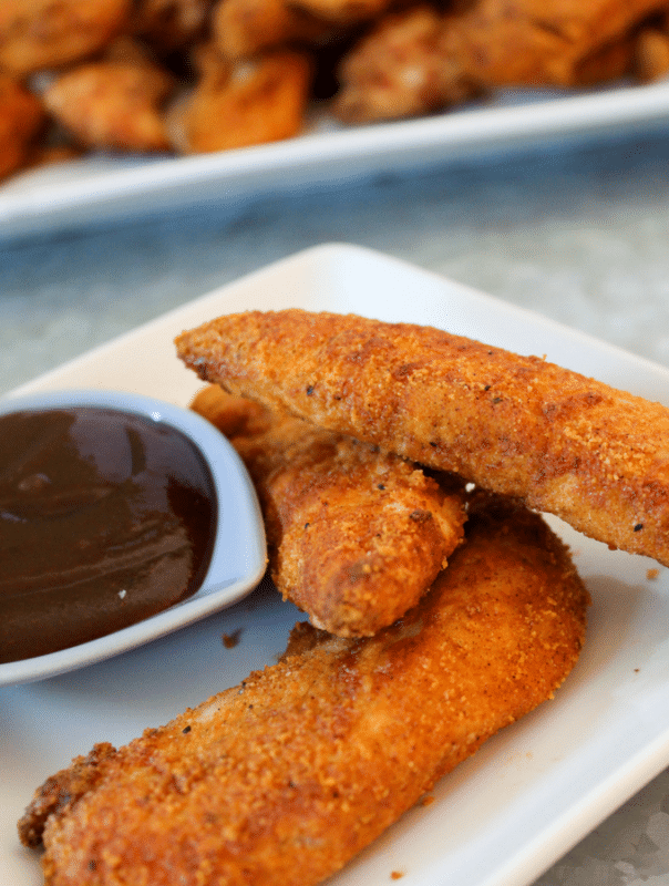 White plate containing 3 Low Carb Crispy Chicken Tenders, side of BBQ.