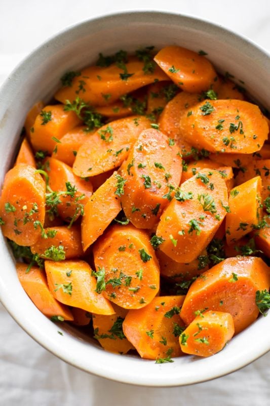 White bowl containing carrots, topped with parsley.