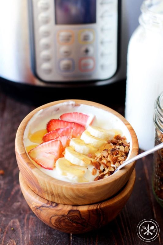 Brown bowl containing homemade Greek Yogurt made in an Instant Pot topped with strawberries, bananas and granola.