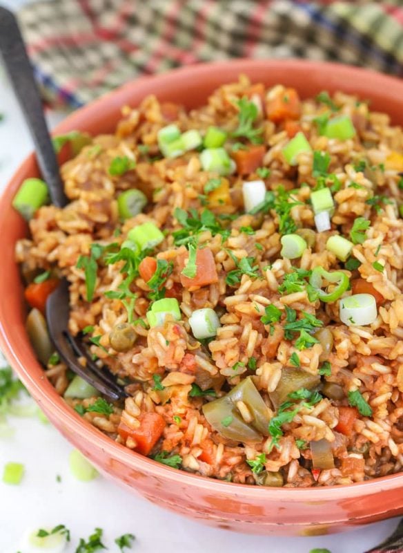 Red bowl containing Teriyaki Instant Pot Rice, topped with scallions, spoon in bowl.