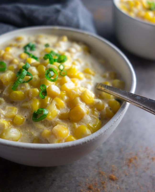 Bowl containing Spicy Creamed Corn made in Instant Pot, topped with scallions.