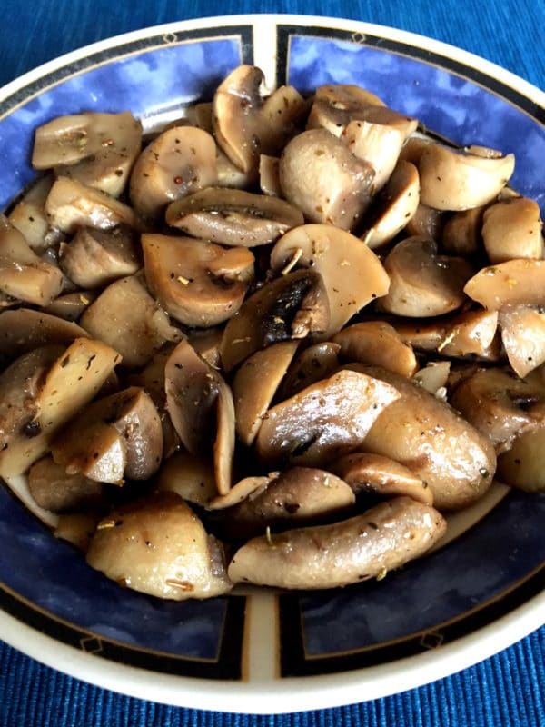 Blue bowl containing sauteed mushrooms cooked in an Instant Pot topped with fresh ground pepper.