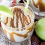 A close up of a glass cup filled with a protein shake, topped with Apple and Caramel.