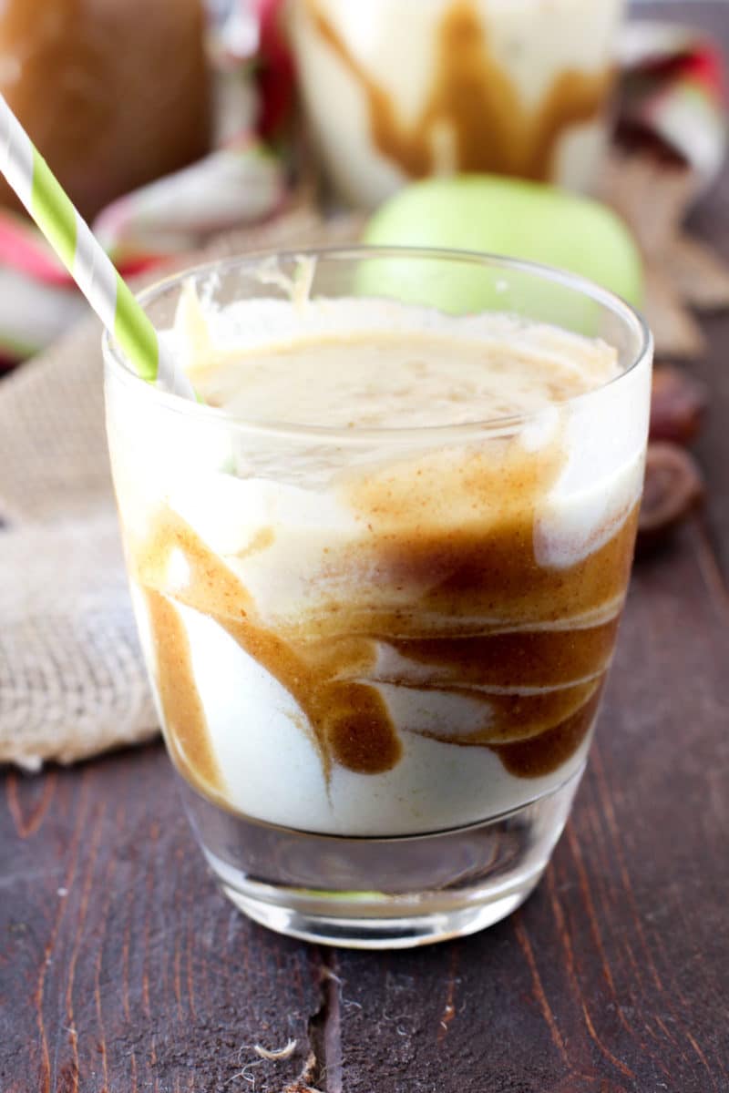 Caramel Apple Protein Smoothie in glass on a wooden table, straw in glass.