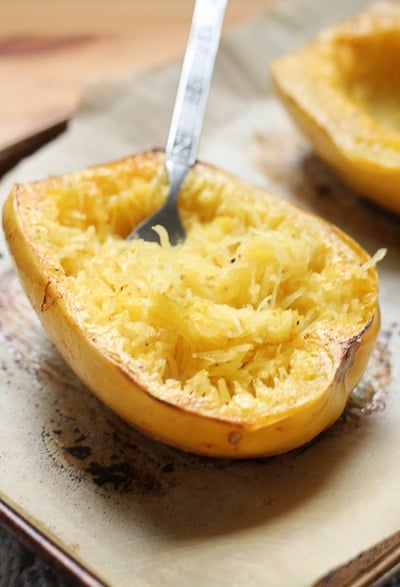 Spaghetti squash with roasted edges fresh out of the oven, fork in squash.