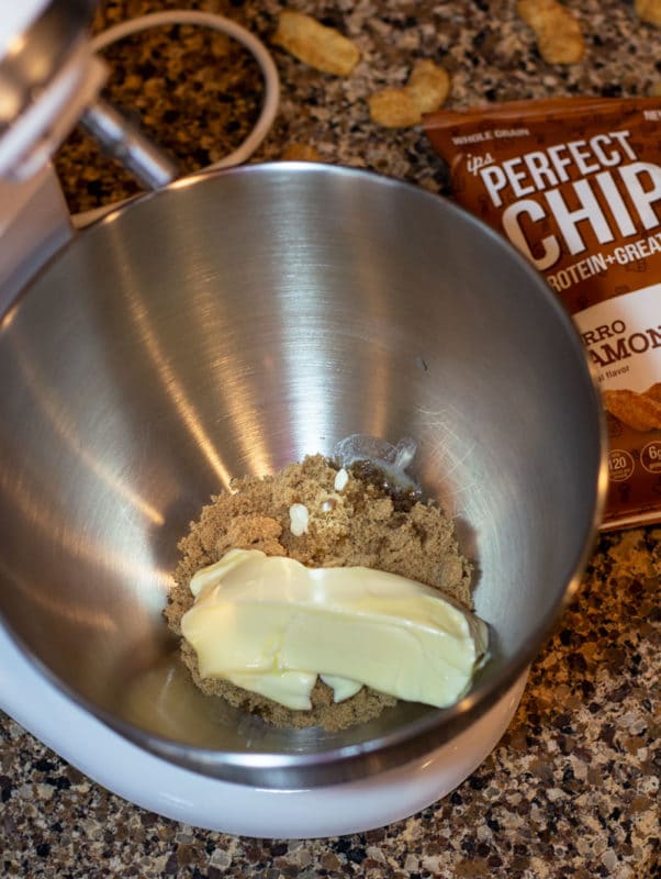 Mixing bowl containing softened butter and brown sugar, ips churro cinnamon chips on counter.