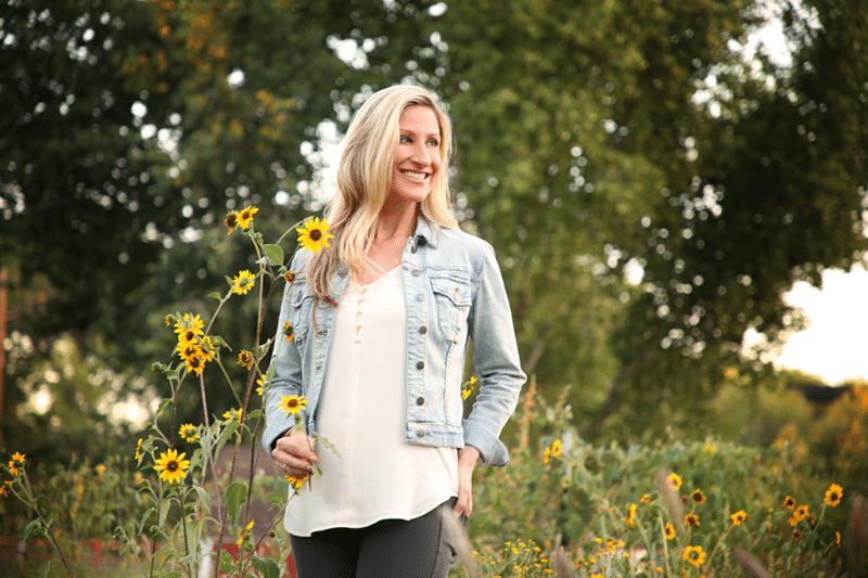Amanda Mason from Recipes Worth Repeating standing a field of sunflowers.