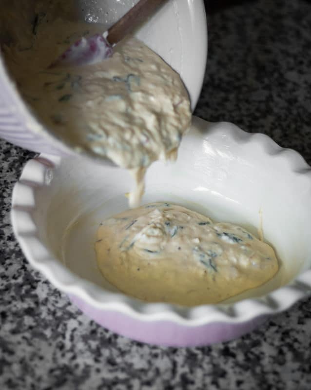 Raw quiche mixture being poured into a pie dish.
