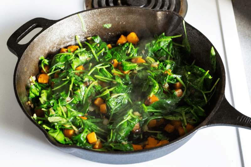 Spinach wilted in a cast iron skillet with butternut squash and onions. 