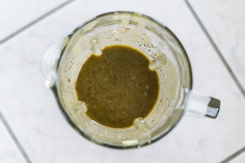 A blender containing pureed pesto sauce. 