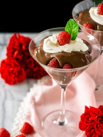 A martini glass of raspberry-mocha pudding parfait with a black background.