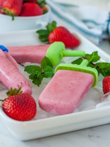 a side view of a strawberry popsicle recipe in a tray with ice