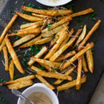 Air Fryer French Fries topped with Parmesan cheese and fresh parsley on a black cutting board.