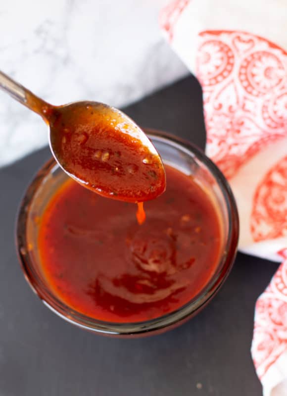Spoonful of homemade BBQ sauce dripping into a bowl.
