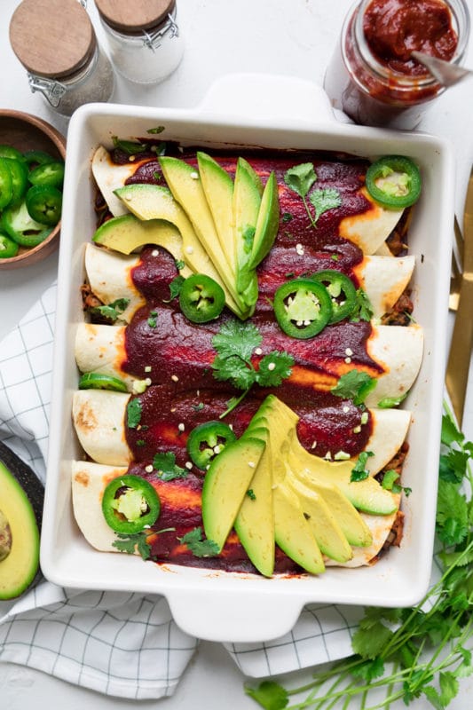 5 Jackfruit enchiladas topped with avocado and jalapeno slices.