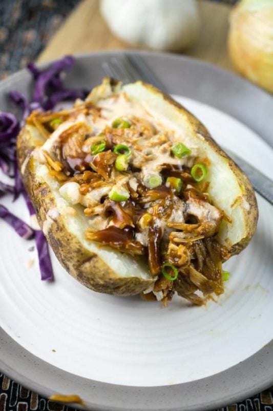 Baked potato topped with pulled jackfruit topped with BBQ sauce and chives.