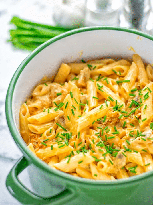 Green bowl containing buffalo jackfruit alfredo pasta topped with chives.