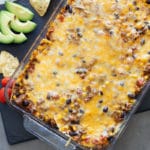 Mexican Style Casserole continuing beef, beans, tomatoes, and cheese, avocado, tomatoes, and tortilla chips on side.