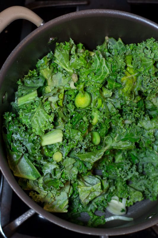 Sauteing sliced leek and kale in a skillet.