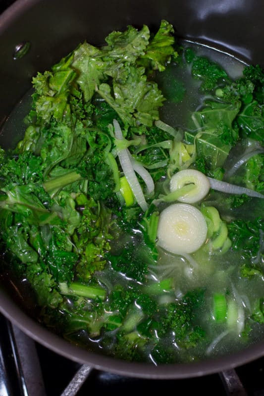 Cooking kale, leeks and chicken broth in a large pot.