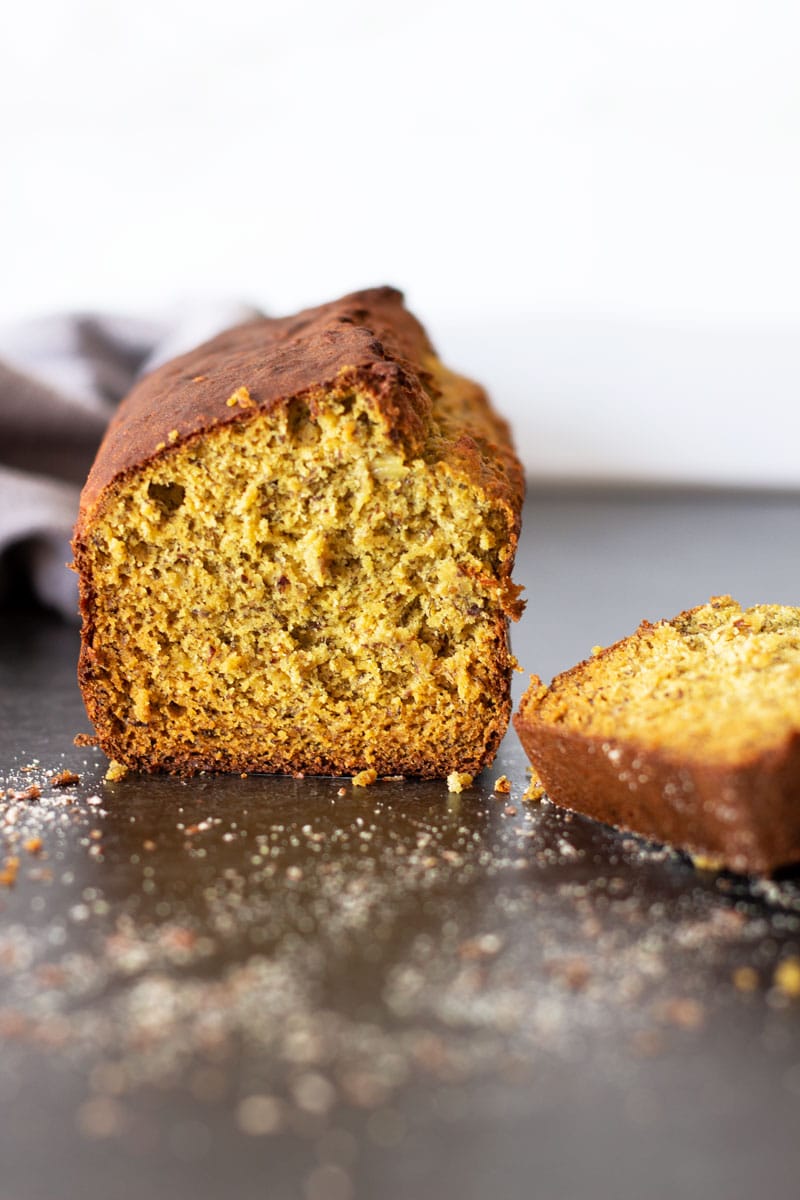 Loaf of quinoa banana bread cut in half, slice on table. 