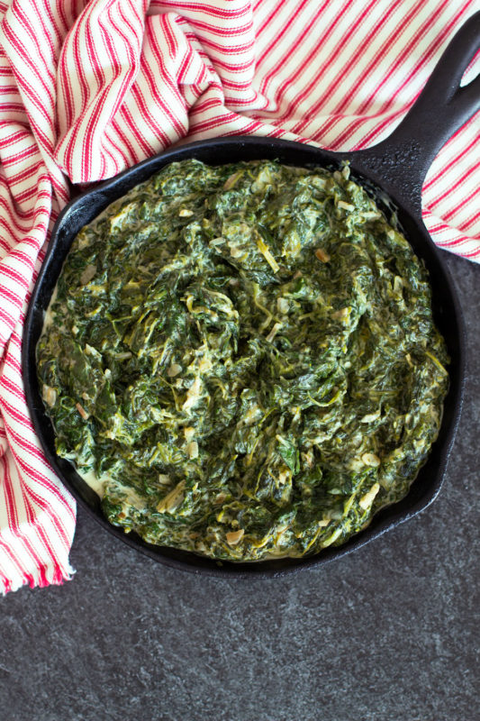 Cast iron skillet containing backed spinach recipe on counter.