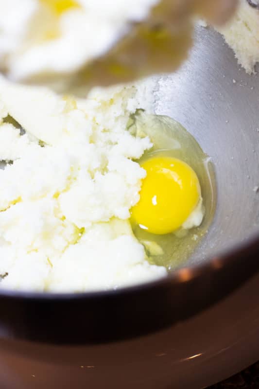 An egg being whisked into butter and sugar.
