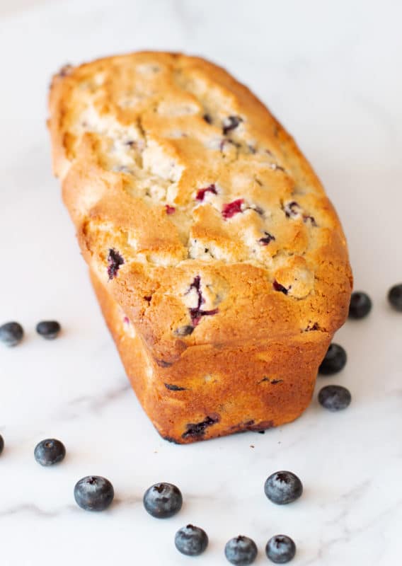 Lemon blueberry loaf on a white counter with blueberries.