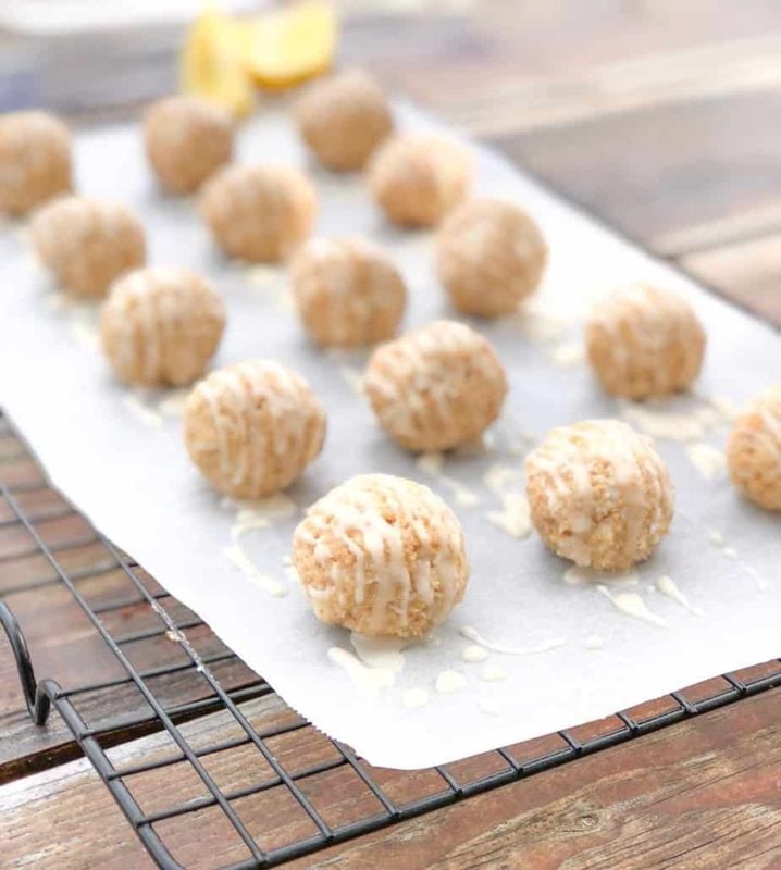 Cheesecake truffles on parchment paper over wire rack with lemon.