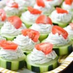 Sliced cucumbers with piped cheese and yogurt topped with tomatoes.