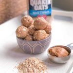 Peanut butter energy balls with oatmeal on table and a measuring cup filling with peanut butter.