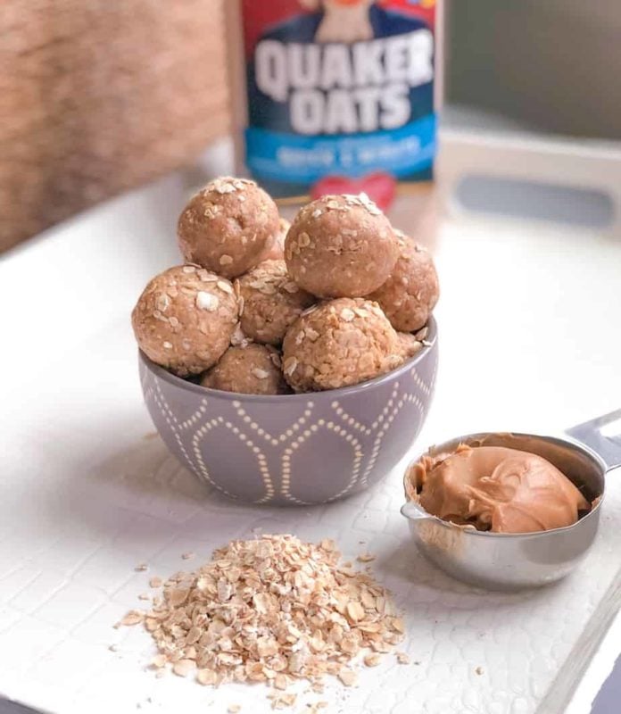 Peanut butter energy balls with oatmeal on table and a measuring cup filling with peanut butter.