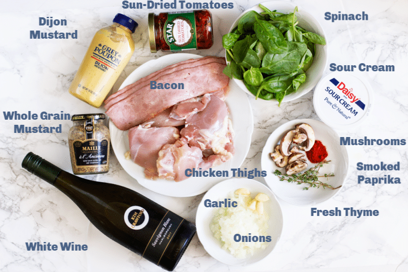 Dijon mustard, sun-dried tomatoes, spinach, sour cream, bacon, chicken thighs, onions, garlic, white wine on counter.