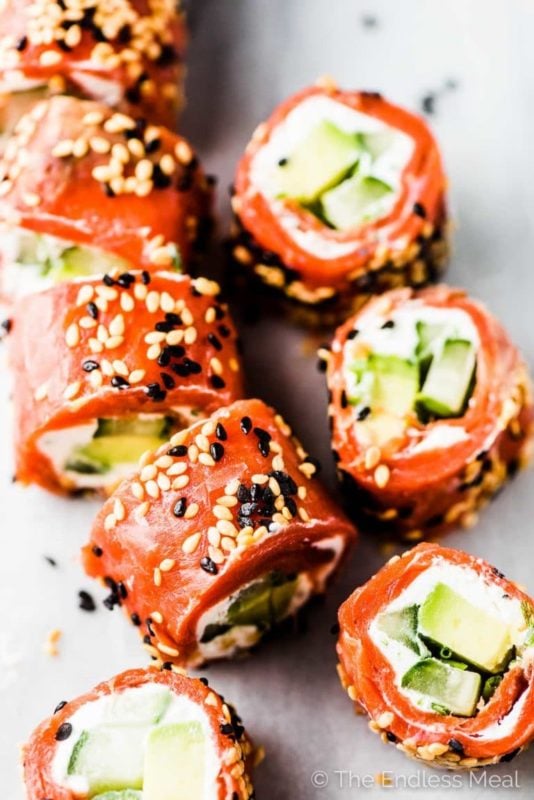 No bake recipe of salmon wrapped in tzatziki, avocado, and coated in sesame seeds sliced.