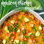 White casserole dish containing mexican casserole topped with green onions, tomato, and avocado.