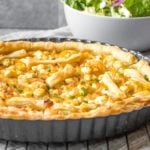 caramelized onion and goat cheese tart in pan with salad behind it