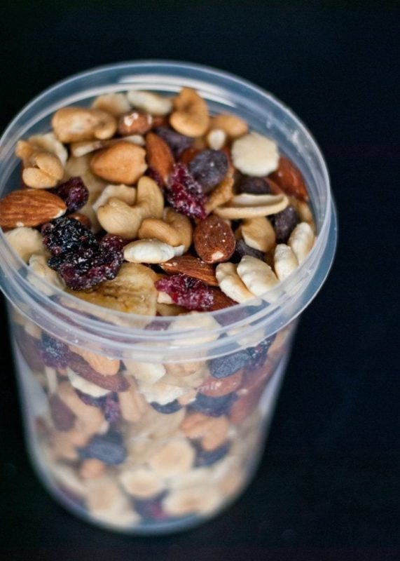 a glass filled with a mix of nuts and raisins