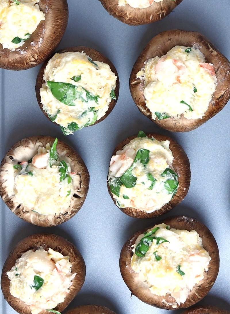 shrimp stuffed mushrooms on a cookie sheet, topped with spinach.