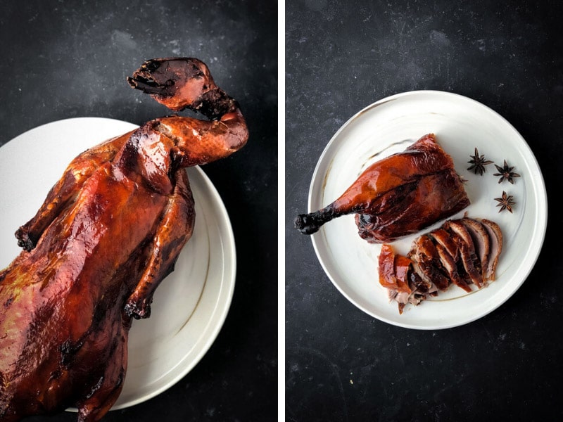 Roasted whole duck on a white plate, sliced.