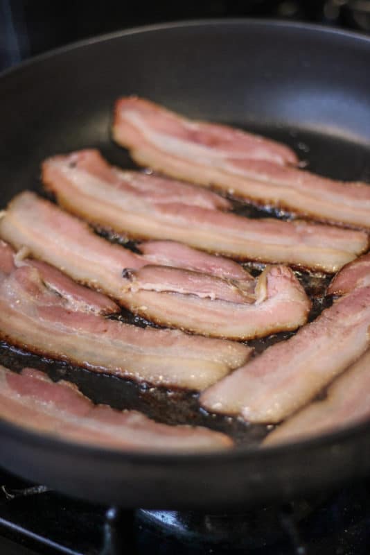 Frying sous vide bacon in a skillet. 