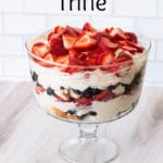 Trifle dish filled with strawberries and blueberries in a custard like mixture.