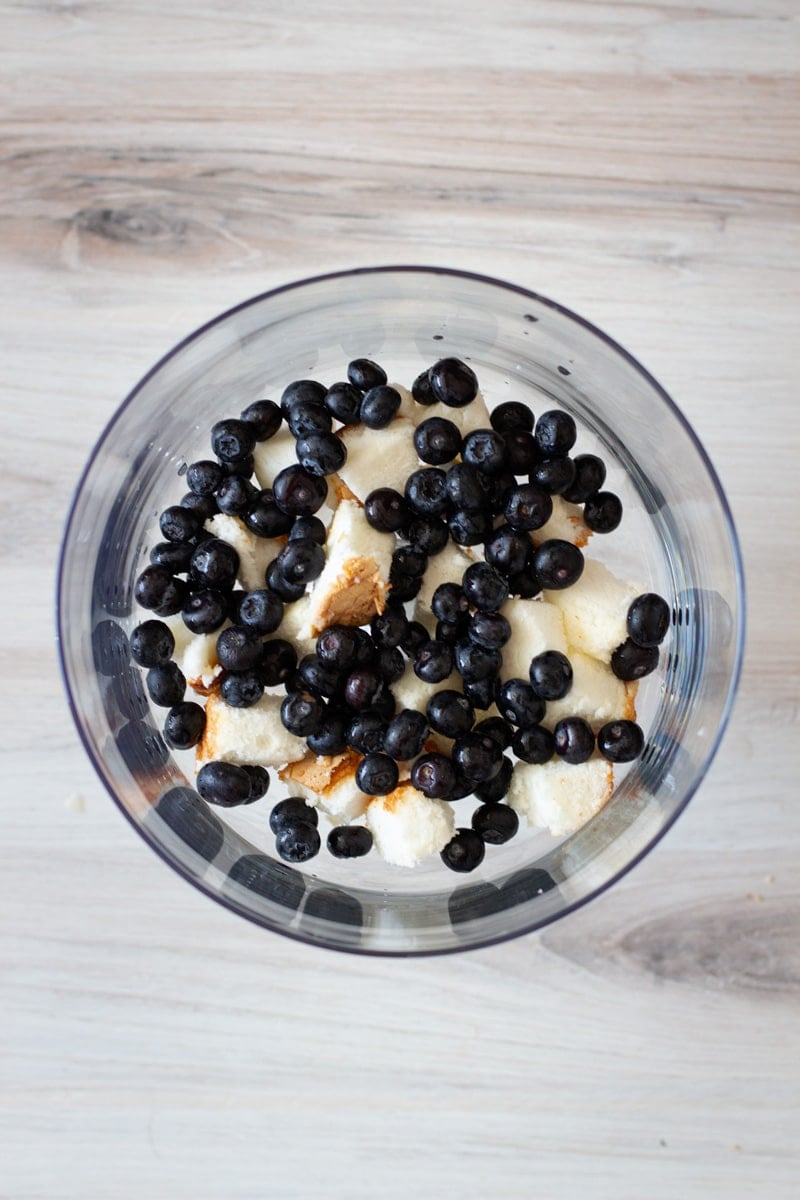 Blueberries layered on top of angel food cake in a glass trifle dish.