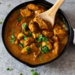 Skillet containing a red chicken curry made in an Instant Pot, topped with fresh cilantro.