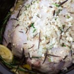 Whole chicken in a crock pot topped with a garlic herb wet rub.