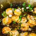 Shrimp being sauteed in a skillet with a ginger garlic sauce.