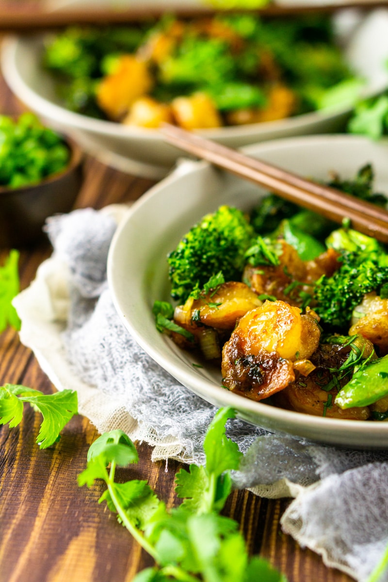 Shrimp stir fry in a bowl with broccoli, chopsticks on bowl.