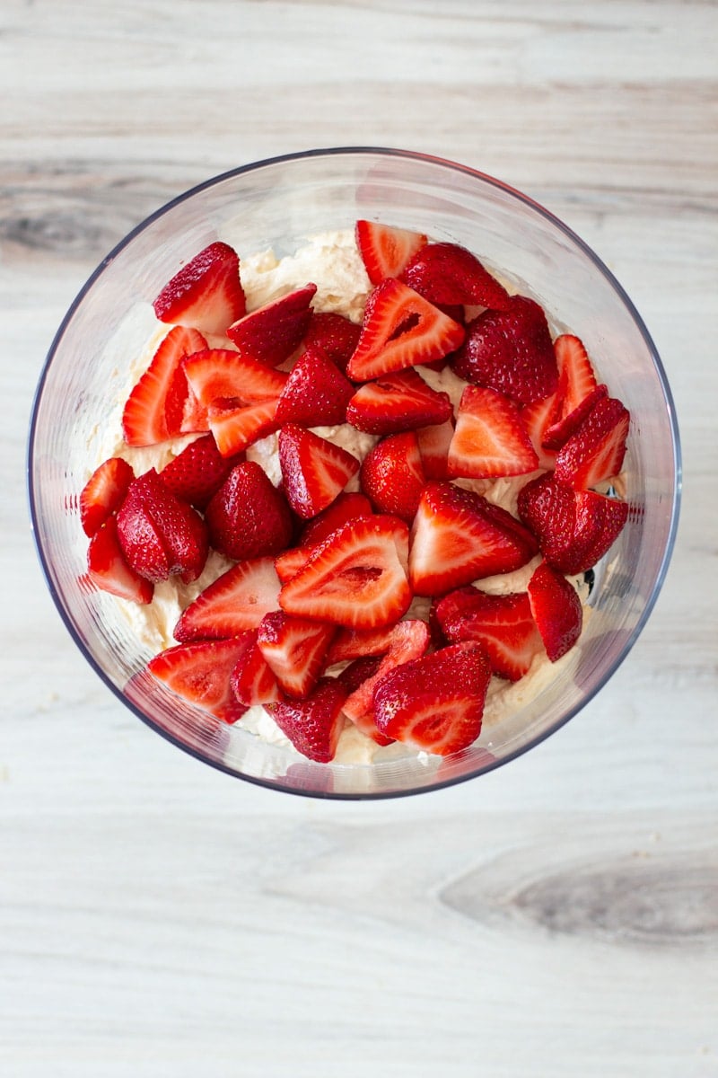 Sliced Strawberries on top of cream in a trifle dish.
