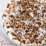Whole pie topped with toasted pecans and shredded coconut sitting on a counter.